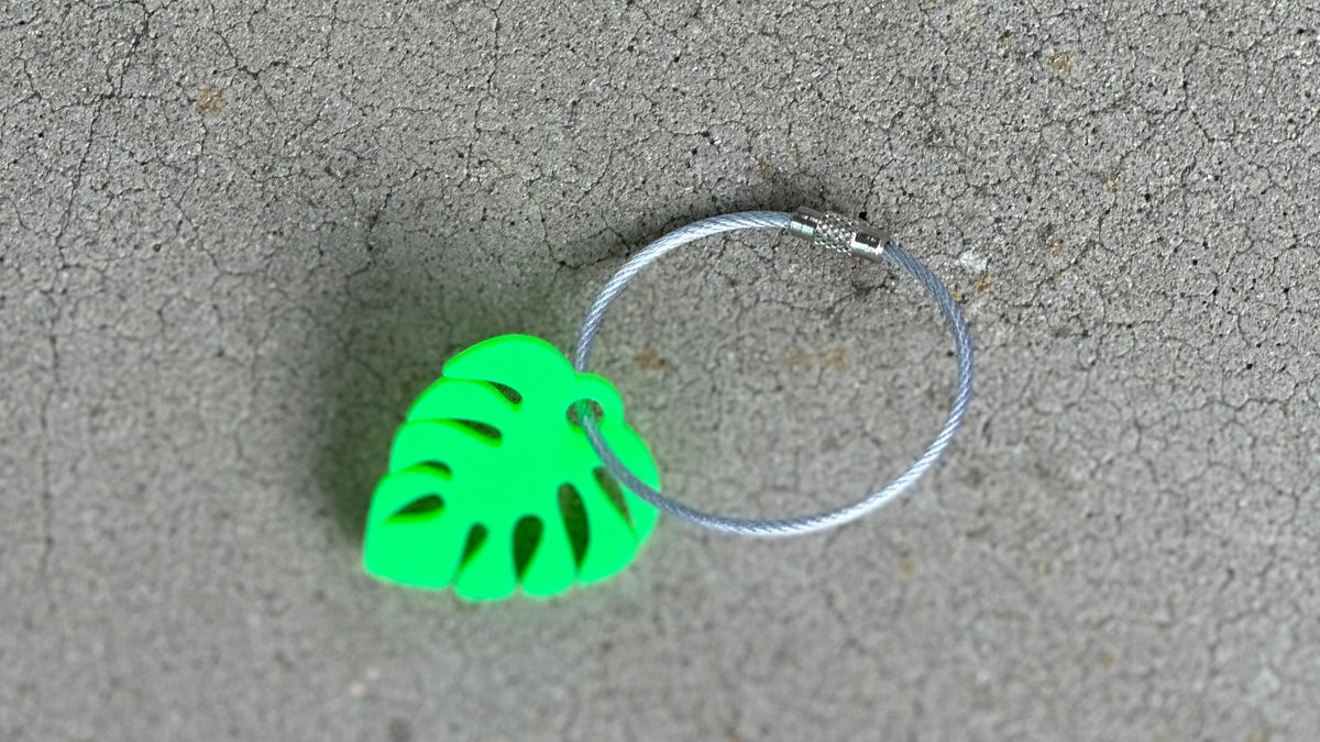 Cute personalized small monstera leaf in bright green with a 2mm silver coated cable wire keychain.